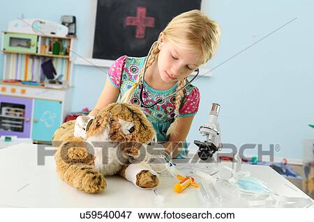 Stock Photo - Girl pretending to be vet examining toy tiger using stethoscope. Fotosearch