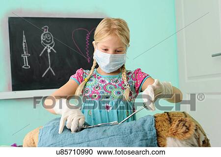 Girl pretending to be vet operating on toy tiger View Large Photo Image Stock Image - Girl pretending to be vet operating on toy tiger. Fotosearch
