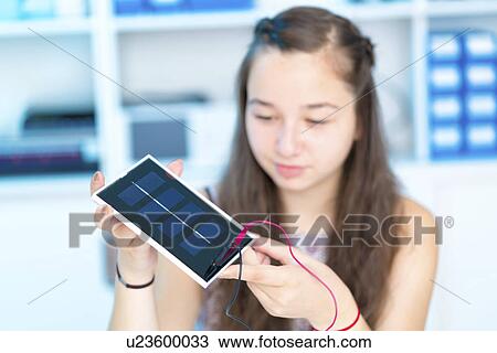 Stock Image - Girl working on solar cell in classroom. Fotosearch