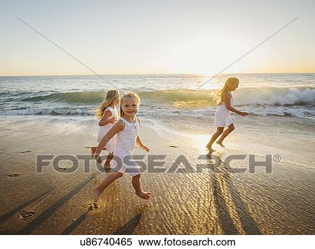 Stock Photography - Girls (4-5, 6-7, 8-9) running on beach. Fotosearch