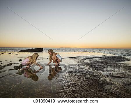 Stock Photo - Girls (6-7, 8-9) playing on beach. Fotosearch