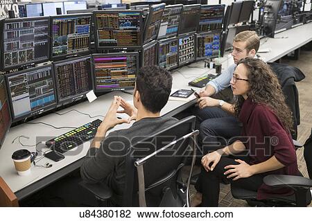 Stock Image - Group of young people analyzing stock market data at trading desk. Fotosearch