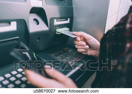 Stock Photo - Hand of young woman inserting credit card into cash machine. Fotosearch