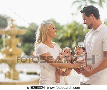 Picture - Happy family with two baby girls (2-5 months) at park. Fotosearch