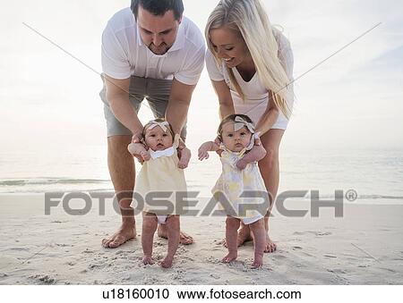 Stock Image - Happy family with two baby girls (2-5 months) at beach. Fotosearch