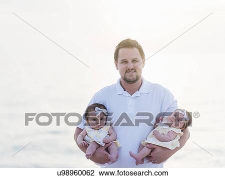 Stock Image - Happy father holding babies (2-5 months). Fotosearch