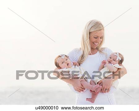 Happy mid adult mother carrying two baby girls (2-5 months) View Large Photo Image Stock Image - Happy mid adult mother carrying two baby girls (2-5 months). Fotosearch
