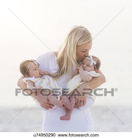 Happy mid adult mother kissing one of baby girls (2-5 months) View Large Photo Image Stock Image - Happy mid adult mother kissing one of baby girls (2-5 months). Fotosearch