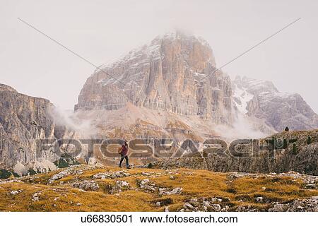 Stock Image - Hiker walking, Mount Lagazuoi in background, Dolomite Alps, South Tyrol, Italy. Fotosearch