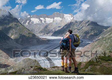 Hiking couple looking out over Aletsch Glacier, Canton Wallis, Switzerland View Large Photo Image Stock Image - Hiking couple looking out over Aletsch Glacier, Canton Wallis, Switzerland. Fotosearch