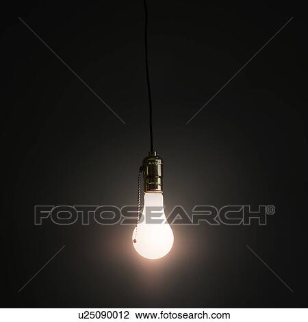 Stock Image - Light bulb hanging against grey background. Fotosearch