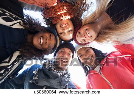Picture - Low angle portrait of five happy adult friends huddled in a circle. Fotosearch