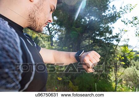 Stock Image - Male runner checking smartwatch in park, Split, Dalmatia, Croatia. Fotosearch