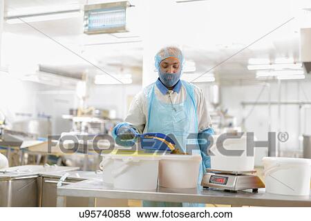 Stock Photo - Male worker weighing curry powder in Asian food factory. Fotosearch