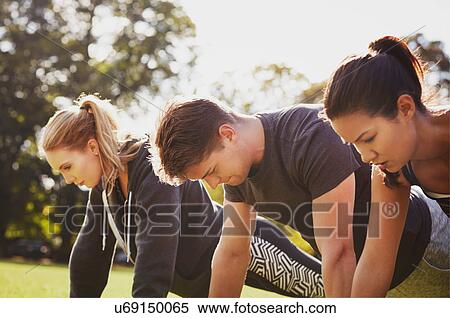Stock Photography - Man and two women doing push up training in park. Fotosearch