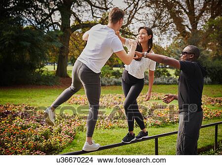 Man and woman with personal trainer balancing on park fence View Large Photo Image Picture - Man and woman with personal trainer balancing on park fence. Fotosearch