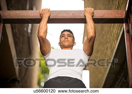 Stock Image - Man doing chin ups, Wapping, London, UK. Fotosearch