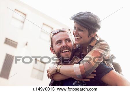 Man giving girlfriend piggyback on street View Large Photo Image Stock Image - Man giving girlfriend piggyback on street. Fotosearch