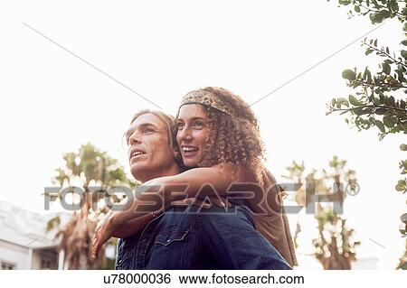 Stock Photograph - Man giving girlfriend piggyback. Fotosearch