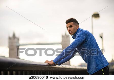 Man standing by riverside, Tower Bridge in background, Wapping, London, UK View Large Photo Image Stock Photograph - Man standing by riverside, Tower Bridge in background, Wapping, London, UK. Fotosearch