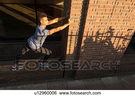 Man stretching and leaning against column View Large Photo Image Stock Photograph - Man stretching and leaning against column. Fotosearch