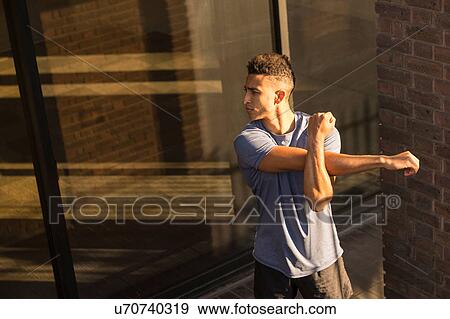 Stock Photo - Man stretching beside column. Fotosearch