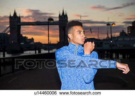 Man stretching by riverside, Tower Bridge in background, Wapping, London, UK View Large Photo Image Stock Photograph - Man stretching by riverside, Tower Bridge in background, Wapping, London, UK. Fotosearch