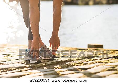 Stock Image - Man stretching on pier. Fotosearch