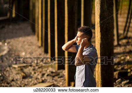 Stock Image - Man stretching under bridge, Wapping, London, UK. Fotosearch