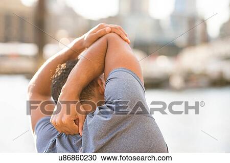 Stock Image - Man stretching, Wapping, London, UK. Fotosearch