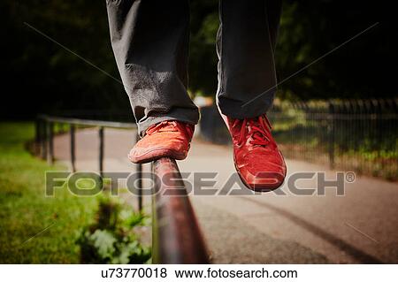 Man training in park, legs and red trainers balancing on fence View Large Photo Image Stock Photo - Man training in park, legs and red trainers balancing on fence. Fotosearch