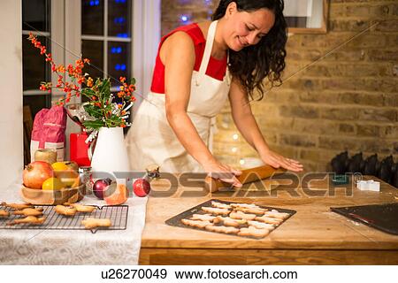 Mature woman rolling Christmas cookie pastry at kitchen counter View Large Photo Image Stock Photo - Mature woman rolling Christmas cookie pastry at kitchen counter. Fotosearch
