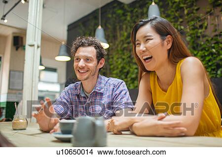 Picture - Mid adult couple talking at coffee shop table. Fotosearch