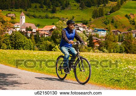 Mid adult man cycling on village path in Vinschgau Valley, South Tyrol, Italy View Large Photo Image Stock Image - Mid adult man cycling on village path in Vinschgau Valley, South Tyrol, Italy. Fotosearch