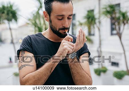 Mid adult man lighting cigarette View Large Photo Image Stock Photo - Mid adult man lighting cigarette. Fotosearch