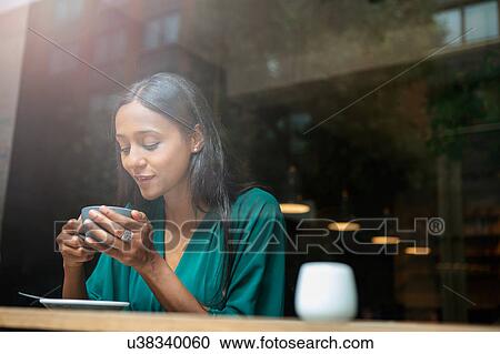 Mid adult woman in cafe window seat looking down at coffee cup View Large Photo Image Stock Image - Mid adult woman in cafe window seat looking down at coffee cup. Fotosearch