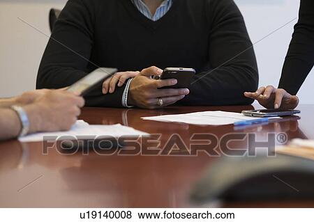 Mid section of business people using mobile phone View Large Photo Image Stock Photo - Mid section of business people using mobile phone. Fotosearch