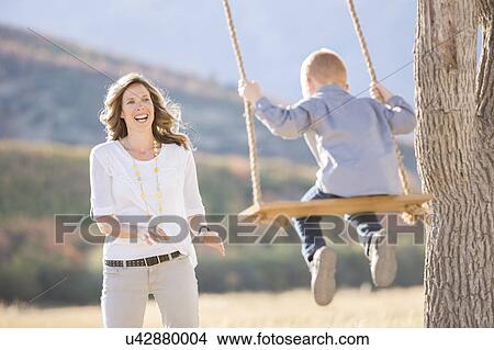 Picture - Mother with child (4-5) sitting on swing. Fotosearch