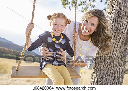 Picture - Mother with girl (4-5) sitting on swing. Fotosearch