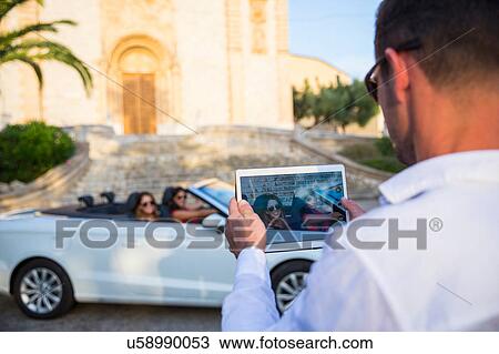 Over shoulder view of man photographing two young women tourists in convertible, Calvia, Majorca, Spain View Large Photo Image Stock Image - Over shoulder view of man photographing two young women tourists in convertible, Calvia, Majorca, Spain. Fotosearch