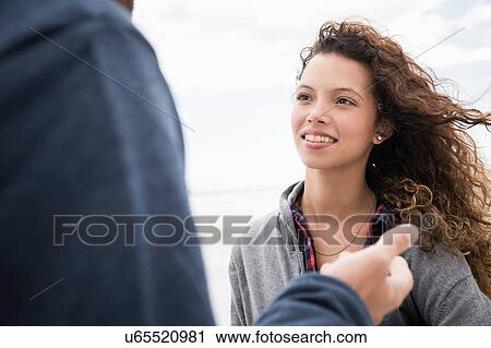 Stock Image - Over shoulder view of young couple talking on beach, Western Cape, South Africa. Fotosearch