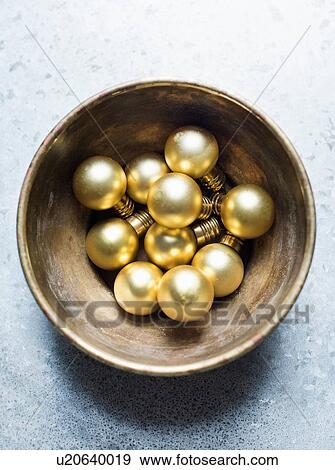 Stock Photo - Overhead view of gold Christmas baubles in bowl. Fotosearch