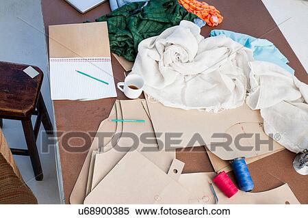 Stock Photography - Overhead view of sketchpad and textiles on fashion design workshop table. Fotosearch
