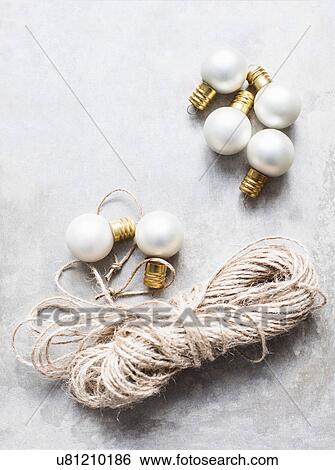 Stock Photograph - Overhead view of white Christmas baubles with string. Fotosearch