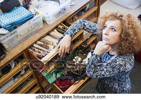 Owner of small fashion business working in material storeroom View Large Photo Image Stock Photo - Owner of small fashion business working in material storeroom. Fotosearch