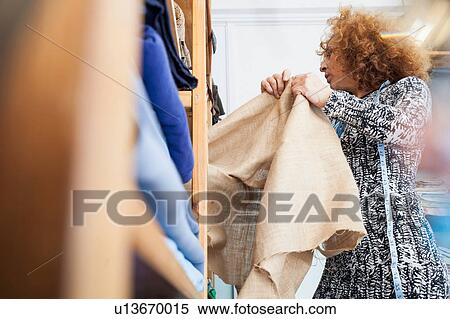 Owner of small fashion business working in material storeroom View Large Photo Image Stock Photography - Owner of small fashion business working in material storeroom. Fotosearch
