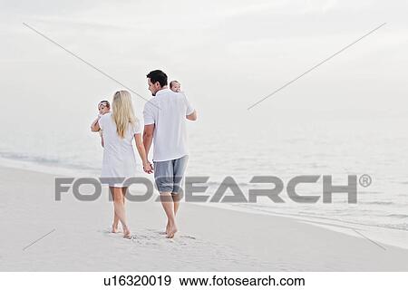 Parents walking with babies (2-5 months) along seashore View Large Photo Image Stock Photo - Parents walking with babies (2-5 months) along seashore. Fotosearch