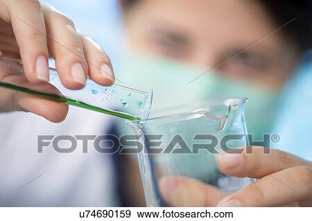 Stock Photo - Person pouring chemical into flask. Fotosearch