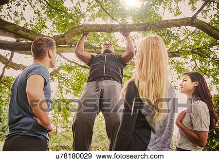 Personal trainer demonstrating pull ups on park tree branch View Large Photo Image Stock Photo - Personal trainer demonstrating pull ups on park tree branch. Fotosearch