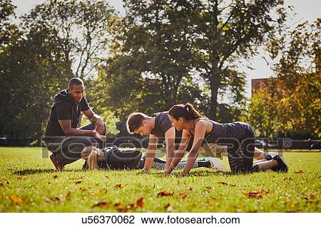 Personal trainer instructing man and women doing push ups in park View Large Photo Image Stock Image - Personal trainer instructing man and women doing push ups in park. Fotosearch